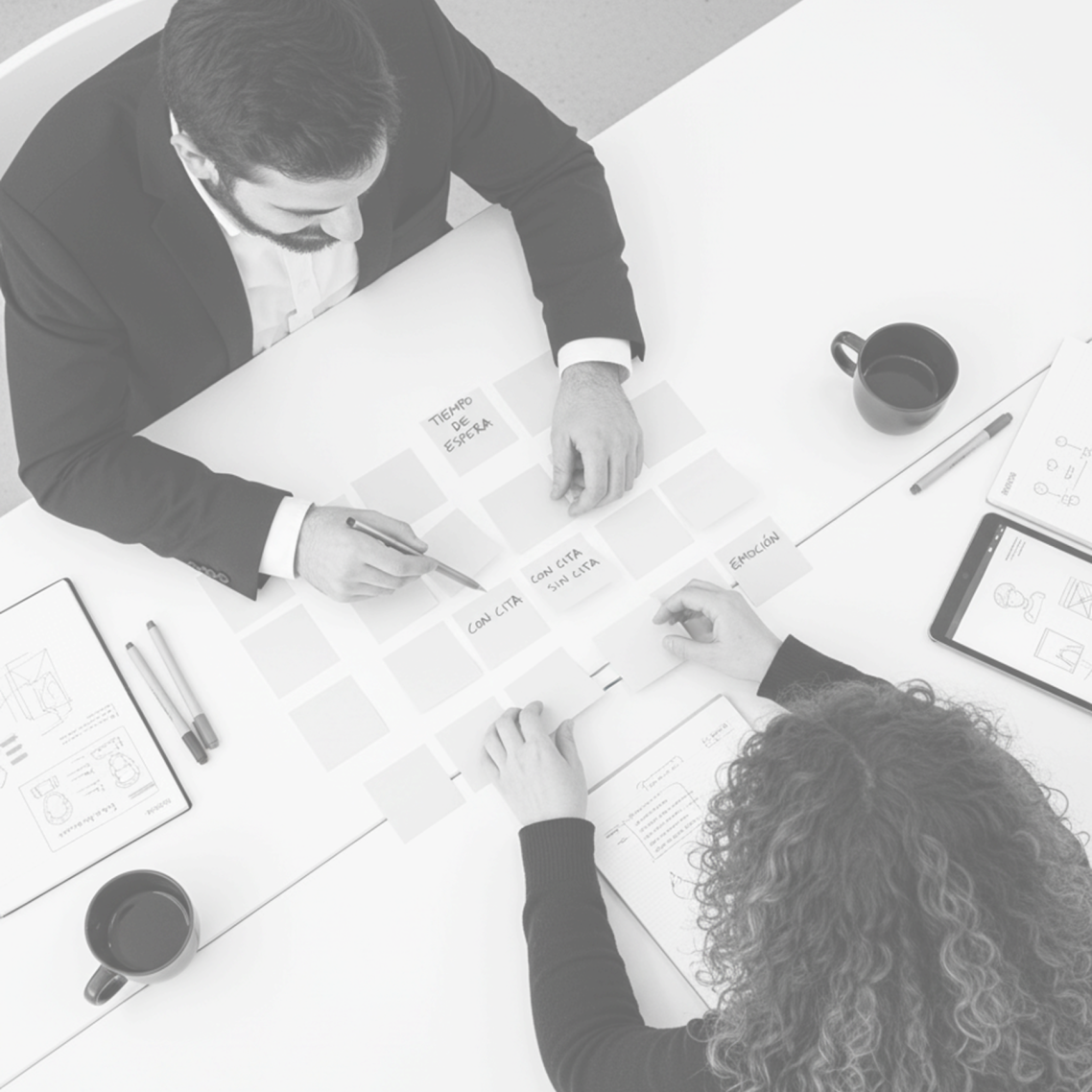 Manos escribiendo en una pizarra con esquemas y notas sobre diseño y procesos.