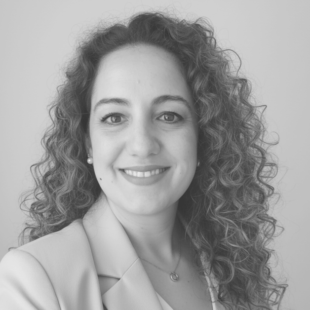 Mujer sonriente con cabello rizado, vestida con chaqueta clara.